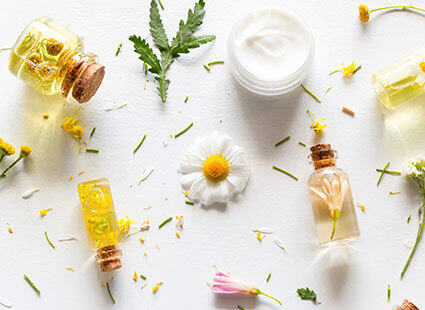 Pure-Ella - Fläschchen mit gelber Flüssigkeit um die Blumen herumliegen