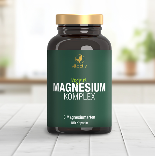 Eine grüne Dose Vitactiv MAGNESIUM KOMPLEX steht auf einem weißen Holztisch.