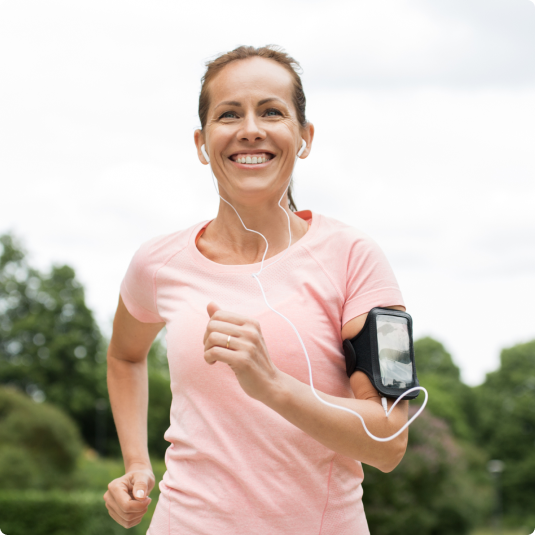 Eine junge Frau im rosafarbenen T-Shirt beim Joggen. Sie lächelt beim Laufen. Sie schwört auf die Magnesium Kapseln von Vitactiv.