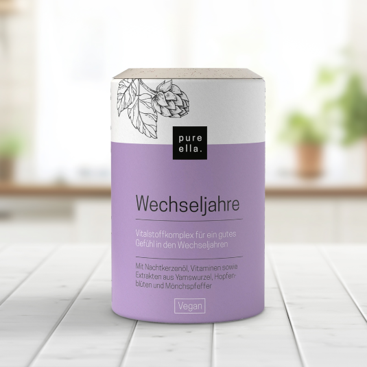 Eine lilafarbene Dose Pure Ella WECHSELJAHRE steht auf einer Küchenanrichte.
